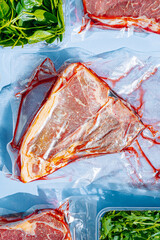 vacuum packed raw beef steaks ready to fry. t-bone steak from marbled beef. meat and vegetables