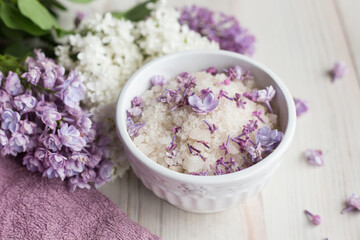 Obraz na płótnie Canvas Homemade bath salt with fresh spring lilac flowers, home healthy spa, relaxation, light wooden background, purple towel, 