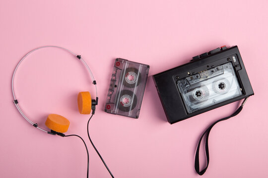 Music listening concept. Vintage cassette tape, audio player and headphones close-up on pink background, top view.