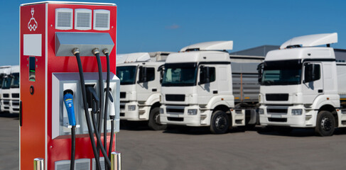 Electric vehicles charging station on a background of a row of trucks. Concept	