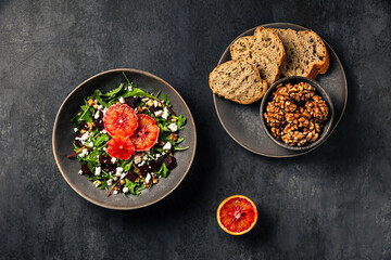 Salad with rocket, chard, beetroot, feta or brynza cheese, walnuts and blood orange. Bread and walnuts. Top view photo.