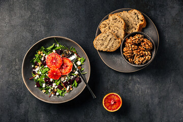 Salad with rocket, chard, beetroot, feta or brynza cheese, walnuts and blood orange. Bread and walnuts. Top view photo.