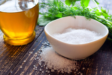 Olive oil, bowl with coarse sea salt, herbs on a wooden background