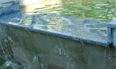 Water flows along a marble cascade and flows down a concrete wall to the next level