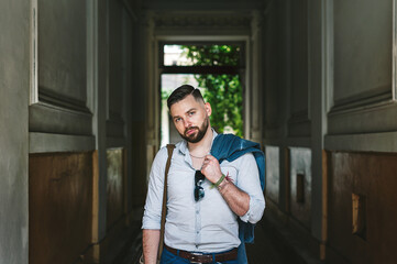 Handsome bearded man holding jacket over shoulder. Street fashion concept.