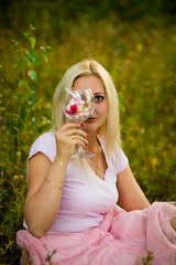 blonde girl with a glass of flowers in summer, selective focus