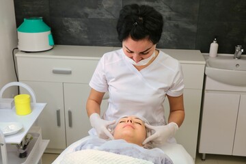 Preparing the face of a female patient for a cosmetic procedure