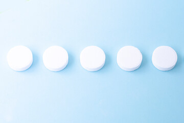 Round white medical pills on a blue background. Health concept