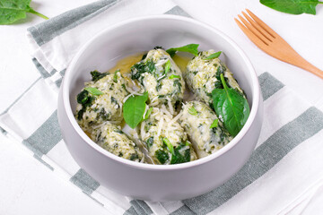 Gnudi with ricotta and spinach served with melted butter with garlic in ceramic bowl. Italian meal