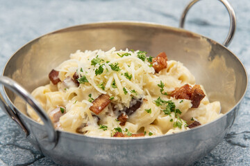 Shiny bowl of macaroni and cheese topped with bits of bacon, parsley, and shredded cheese.