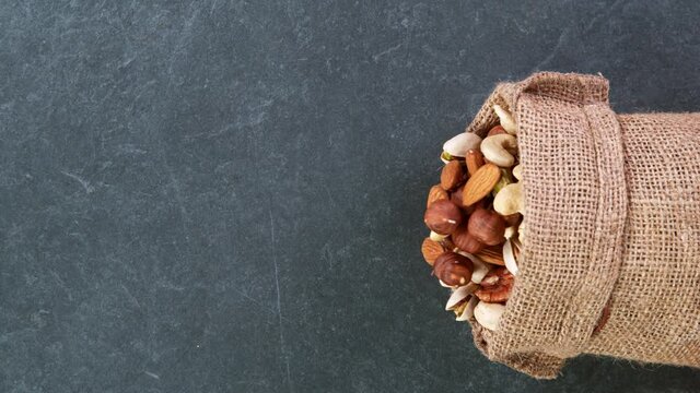 Super slow motion of falling mix nuts in jute bag.