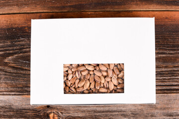 Roasted salted pistachios in a sealed box on a wooden background