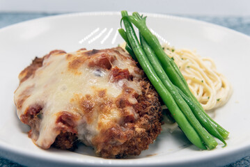 Breaded chicken parmesan served with cheesy pasta and topped with green beans for a delicious dinner meal.