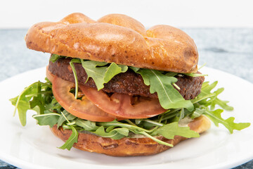 Health conscious vegans can enjoy this vegan burger served with arugula, tomoatoes, and stacked inside a bun