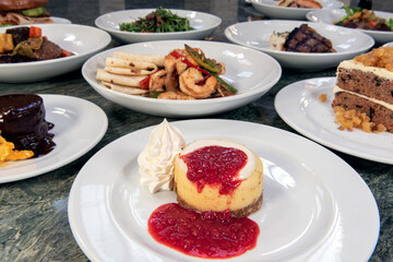 Full table of a variety of restaurant dishes to choose from with New York Style Cheesecake in the center.