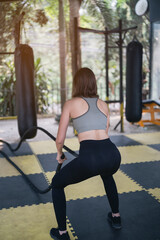Fototapeta na wymiar beautiful women exercise training with bettle rope in the gym, sport fitness concept