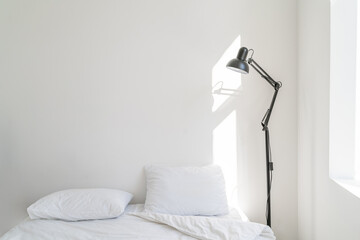 Wall white bedroom bed, pillow and fresh linens.  morning bright sunbeams shine. minimalistic black lamp floor lamp Stylish modern simple rustic or scandinavian style design Pure and clean. Copy space