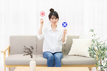 窓際のソファに座ってOKのプラカードを持つ若い女性