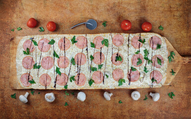 One meter pizza. Long pizza with ham and herbs lies on a wooden table. Roman pizza on a wooden...