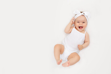 smiling newborn baby on a white bed at home, the concept of a happy, healthy baby, a place for text - obrazy, fototapety, plakaty