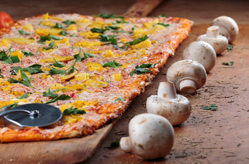 Long pizza with chicken and pineapple lies on a wooden table. Roman pizza on a wooden spatula. One...