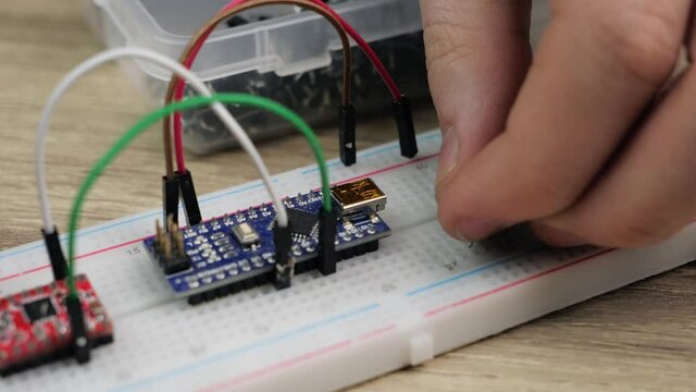 Working with electronics microcircuits on a breadboard, the hand of a white man arranges microcircuits, the concept of working with electrical modules and programming