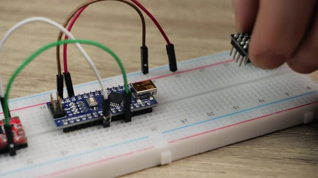 Working with electronics microcircuits on a breadboard, the hand of a white man arranges microcircuits, the concept of working with electrical modules and programming
