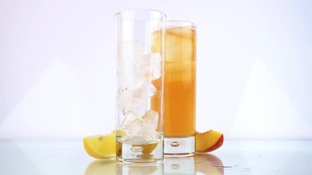 Pouring Peach and Lemon Ice Tea in a Glass isolated on white Background