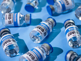 Glass vials for Covid-19 vaccine on blue background. Group of Coronavirus vaccine bottles.