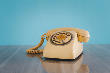 Vintage old phone on the table in front of sky blue background.