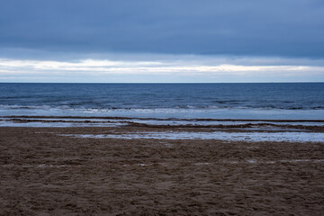 icy winter beach near the sea with frozen sand and ice blocks in the water
