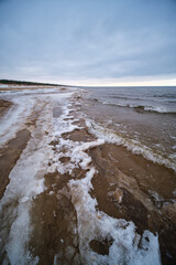 icy winter beach near the sea with frozen sand and ice blocks in the water