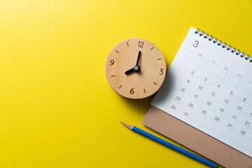 close up of calendar, pencil, alarm clock on the yellow table background, planning for business meeting or travel planning concept