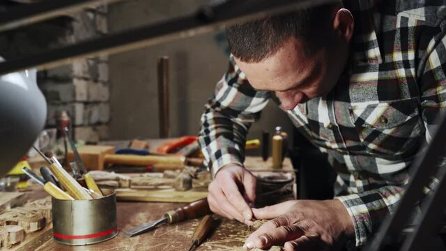 Young adult male working with wood in own workshop side view