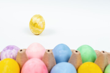 Fototapeta na wymiar Focus on golden Easter egg decorated with glitter. Easter eggs on a white background. Blurred colorful Easter eggs in front of