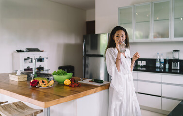 Ethnic young woman drinking water in modern kitchen in morning