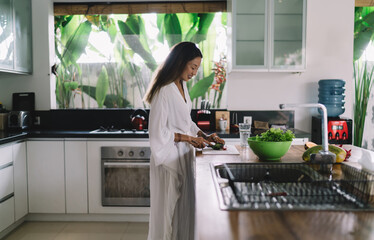 Smiling young ethnic female preparing healthy breakfast in kitchen