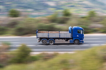 Truck with three axles driving fast on the highway with the rest of the moving image, creating a...