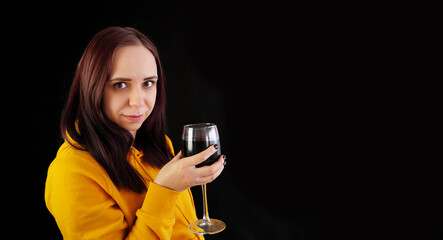 Relaxed young woman poses with glass of red wine on black background. Adult happy brunette resting with alcohol in her weekend.