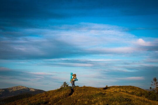 Tourist on Mountain ridge. Man with backpack hiking. Silhouette on blue sky background. Seasonal photo in cold tones
