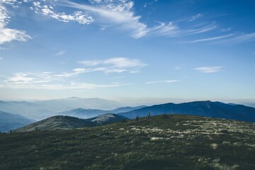 Fototapeta na wymiar Mountain tracking. People in distance on blue sky background. Seasonal photo in cold tones