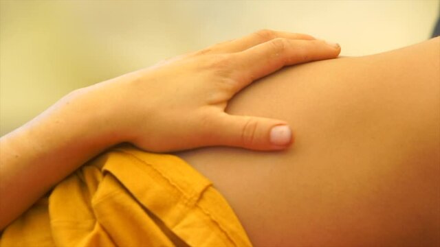 the dancers palm rests on the thigh in a yellow dress. lying on the floor 