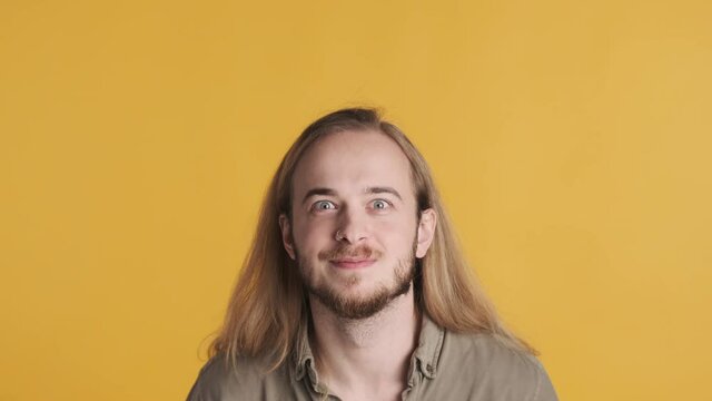 Amazed blond berded guy keeping hands on head happy to hearing good news isolated on colorful background. Rejoicing man