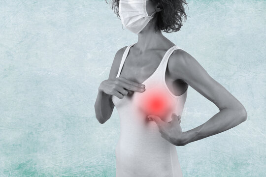 White Woman With A Surgical Mask For The Coronavirus Palpating Her Breast For The Prevention Of Breast Cancer. Bluish Background.