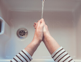 Point of view of woman washing her hands under a running water from a tap