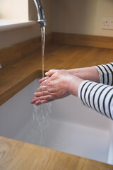 woman washing her hands under a running water tap