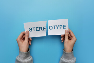 A man tears up a paper with the inscription: stereotype. A symbol of breaking stereotypes in life - obrazy, fototapety, plakaty