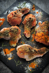 Raw chicken wings with spices are marinated on a stone board. Buffalo wings cooking.