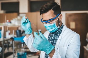 Middle age scientist and researcher with face protective mask work in chemical laboratory on...
