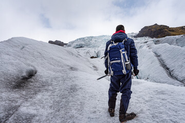 A man in hiking, climbing gear standing on the Solheimajokull glacier ice in Iceland
